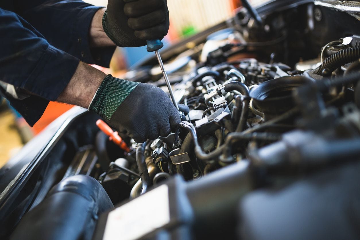 A mechanic repairs a car engine